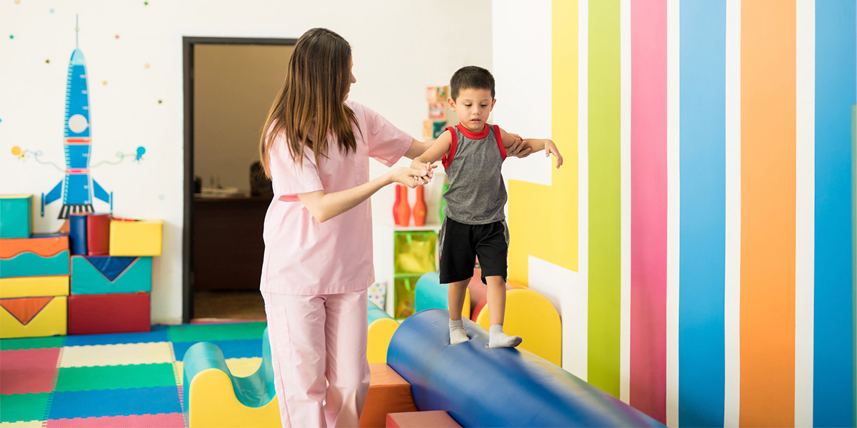 Child walking on balance beam at therapy