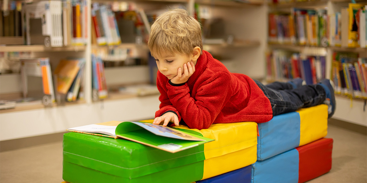 Child laying down reading a book